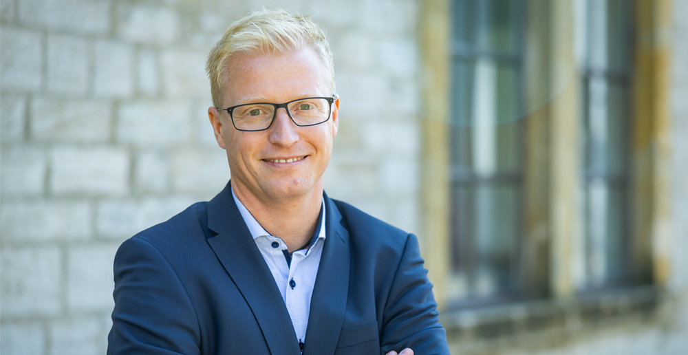 Portrait Dr. Six neuer Geschäftsführer Markt vor einem steinernen Gebäude